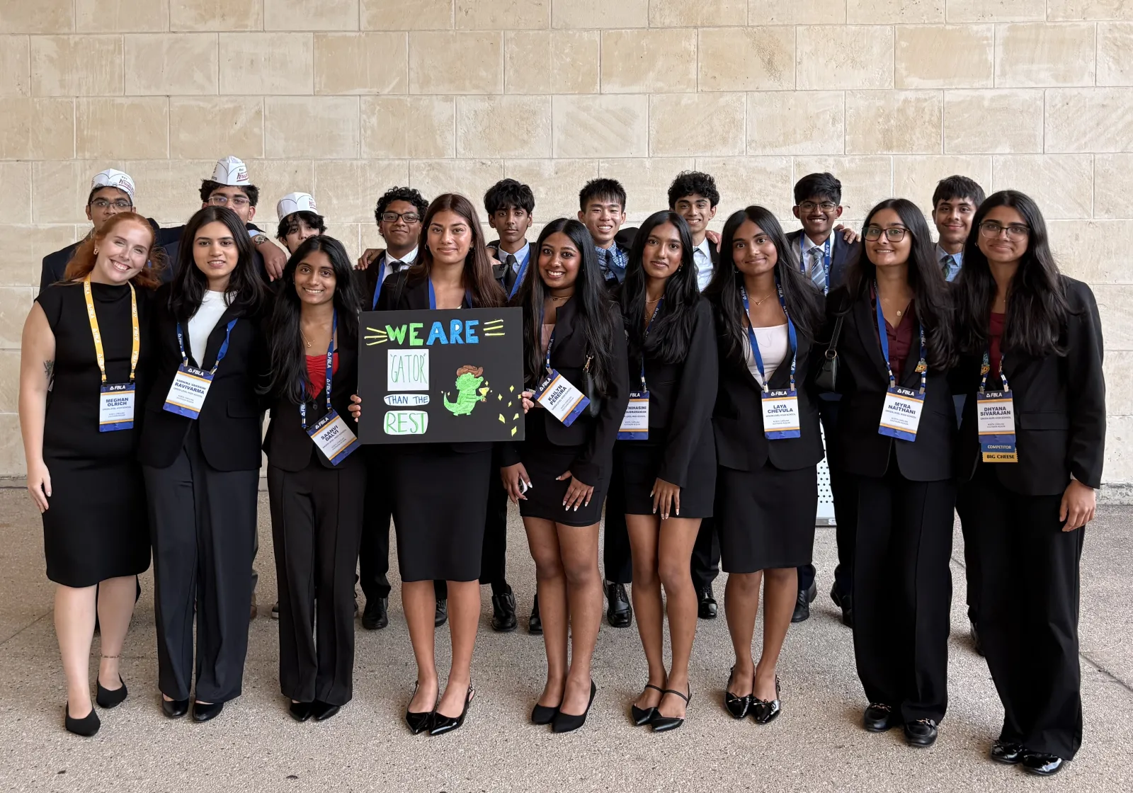 Green Level FBLA members together at a conference, holding a sign that reads “We are gator than the rest”